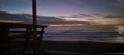 a bench sitting on the beach with a sunset at Domos Curiñanco vista al mar in Valdivia