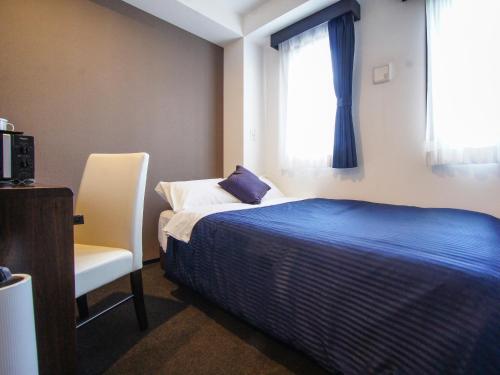 a bedroom with a bed and a chair and a window at HOTEL LiVEMAX Sagamihara Ekimae in Sagamihara