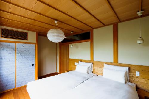 sypialnia z 2 białymi łóżkami i sufitem w obiekcie hotori w mieście Kioto
