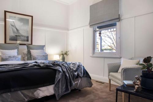 a bedroom with a bed and a chair and a window at Birch House in Daylesford