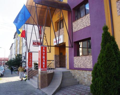 un edificio púrpura y amarillo con una persona que pasa por delante en Orizont Hotel en Suceava