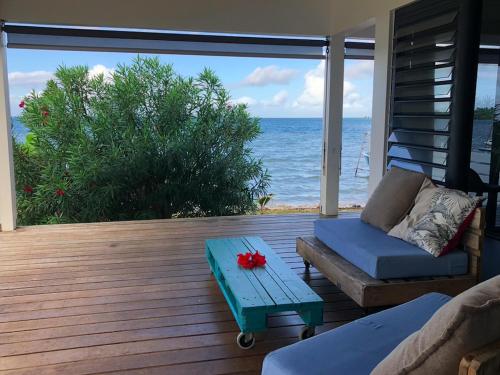 a deck with a couch and a table and the ocean at Faaroa Villa in Uturoa