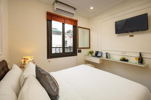 a bedroom with a white bed and a flat screen tv at TrangTrang Classy Hotel in Hanoi