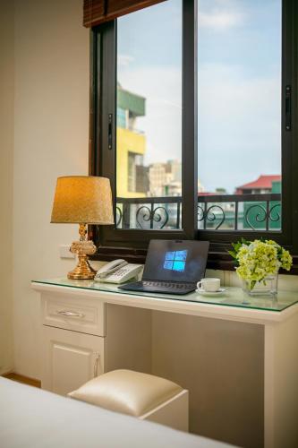 a desk with a laptop computer and a window at TrangTrang Classy Hotel in Hanoi