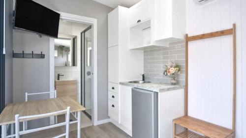 a small kitchen with white cabinets and a table at Tiny House Stays House 1 in Sanctuary Point