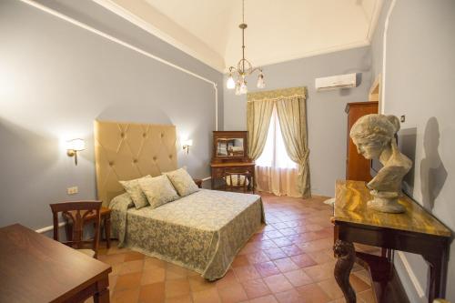 ein Schlafzimmer mit einem Bett und einem Tisch mit einer Statue in der Unterkunft Palazzo Raho in Cefalú