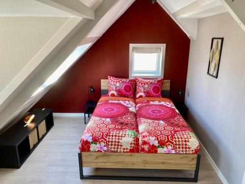een slaapkamer met een bed met rode muren bij Glücklich am Meer Meerblick mit Wellnesszugang in Egmond aan Zee