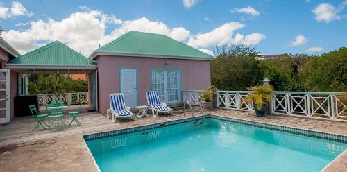 - une piscine avec 2 chaises et une maison dans l'établissement Mandevilla Nevis, à Cliftons