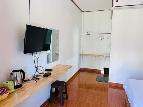 Habitación con TV en la pared y mesa. en บ้านชมดาวรีสอร์ทบึงโขงหลง en Ban Don Klang