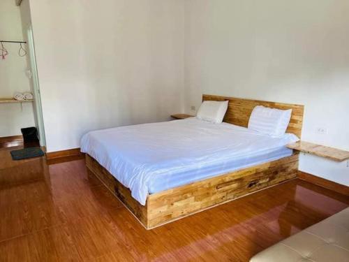 Schlafzimmer mit einem Holzbett mit weißer Bettwäsche in der Unterkunft บ้านชมดาวรีสอร์ทบึงโขงหลง in Ban Don Klang