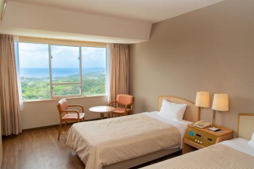 a hotel room with two beds and a large window at Motobu Green Park and Golf Course in Motobu