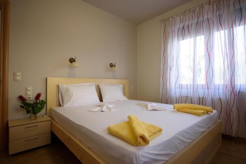 um quarto com uma cama branca e toalhas amarelas em Apartment Mythos Myrto em Pitsídia