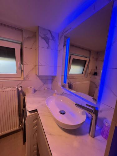 baño con lavabo y espejo con luces azules en The Nice Apartment, en Domžale