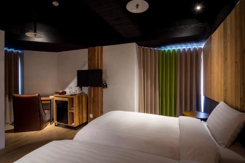 a bedroom with a white bed and a green curtain at Calligraphy Greenway Hotel in Taichung
