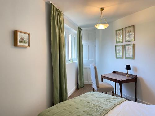 1 dormitorio con escritorio, 1 cama y 1 mesa en L'Orangerie des Ursulines en Bayeux