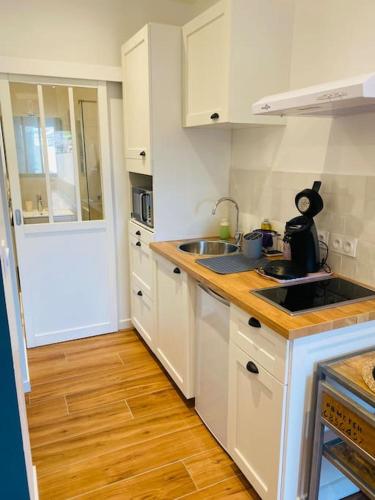 une cuisine avec des armoires blanches et un plancher en bois dans l'établissement Studio du château climatisée, à Carcassonne