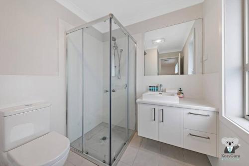 y baño con ducha, aseo y lavamanos. en KozyGuru / Austral / 5Bed House / NAU015, en Horningsea Park
