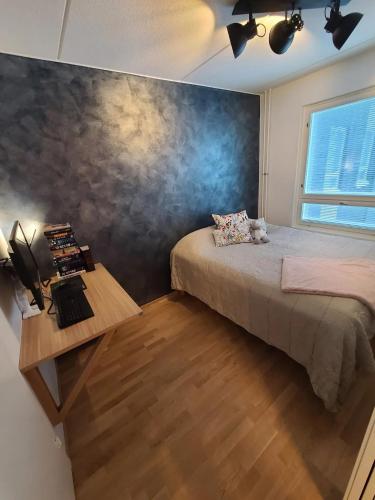 a bedroom with a bed and a desk and a window at Cosy apartment with a relaxing sauna and a balcony in Helsinki
