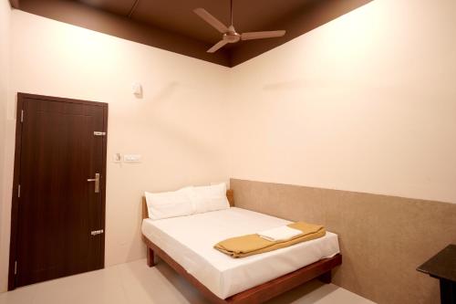 a small bedroom with a bed and a brown door at Reach Residency in Cochin