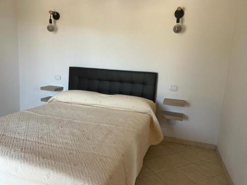 una camera da letto con letto con testiera nera e luci di Agriturismo Il Giardino Degli Olivi Appartamenti a Castiglione della Pescaia