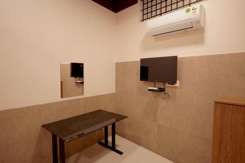 a room with a table and a tv on the wall at Reach Residency in Cochin
