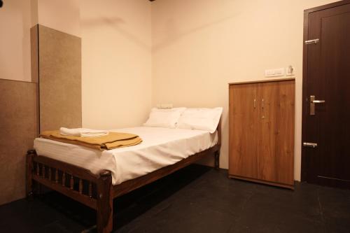 a small bedroom with a bed and a wooden cabinet at Reach Residency in Cochin