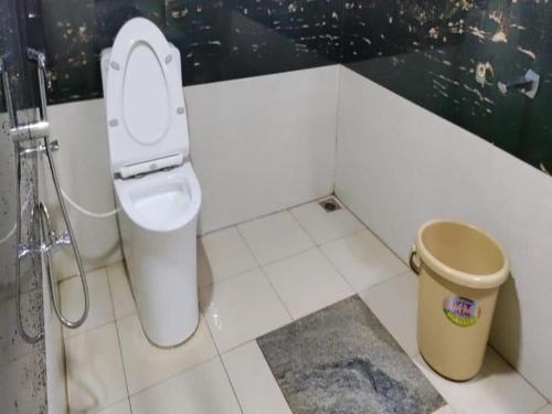 a bathroom with a toilet and a trash can at Nature Valley Homestay Near Annapoorneshwari Temple in Kalasa