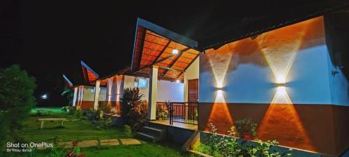 a house with lights on the side of it at night at Nature Valley Homestay Near Annapoorneshwari Temple in Kalasa
