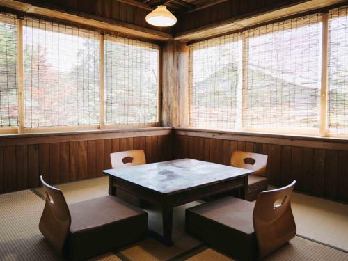 a dining room with a table and chairs and windows at RITA Izumifumoto in Izumi