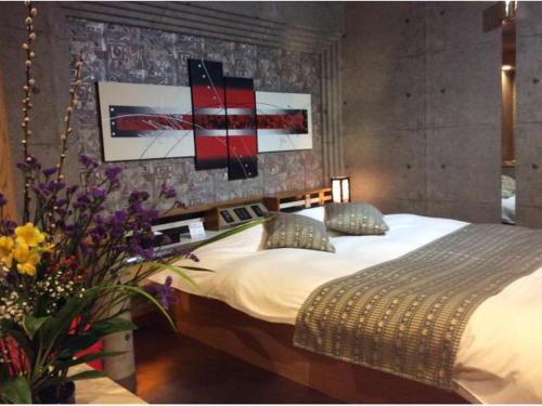 a bedroom with a bed and some flowers and pictures at HOTEL GEN 猪名川店 in Yamashita