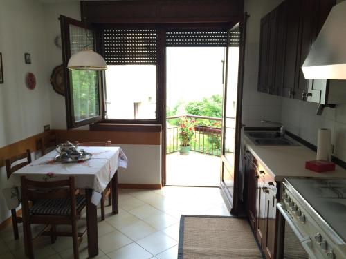 eine Küche mit einem Tisch und Blick auf einen Balkon in der Unterkunft Casa Betulla in Rovereto