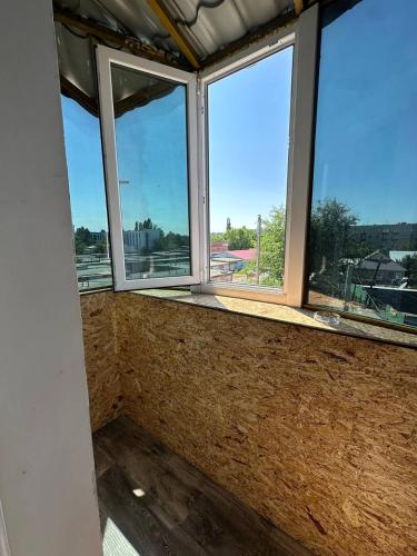 an empty room with three windows in a building at Sport Hotel Terra in Ustʼ-Kamenogorsk