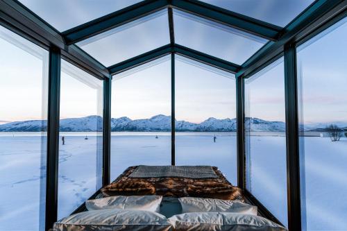 a glass house with a view of the snow covered mountains at Aera - Glass cabins in Tromsø