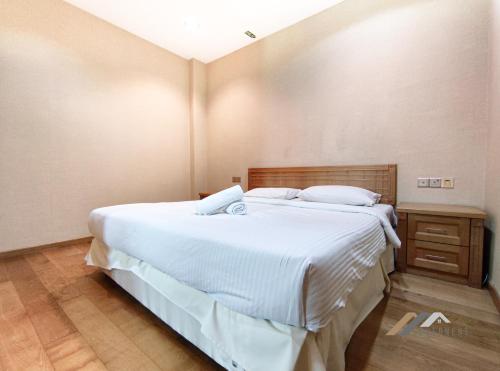 a bedroom with a large white bed and a wooden cabinet at Mciti Suites by Evernent in Miri