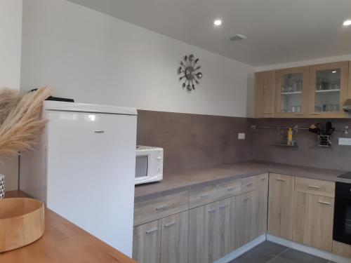 a kitchen with wooden cabinets and a white microwave at la java in Saint-Cyran-du-Jambot