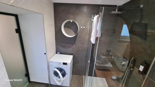 a bathroom with a washing machine and a mirror at HIŠA KAPIŠ with HOT TUBE in Koper