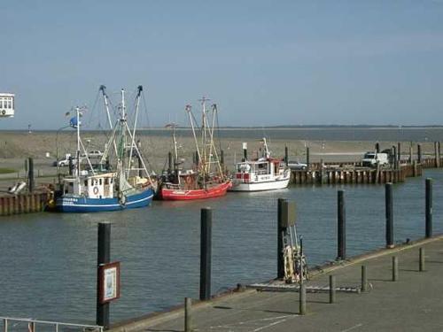 three boats are docked at a dock in the water at Ferienwohnung in Dornumersiel 20-068 in Dornumersiel