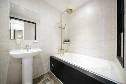 a white bathroom with a sink and a bath tub at Brown Dot Hotel Angang in Gyeongju