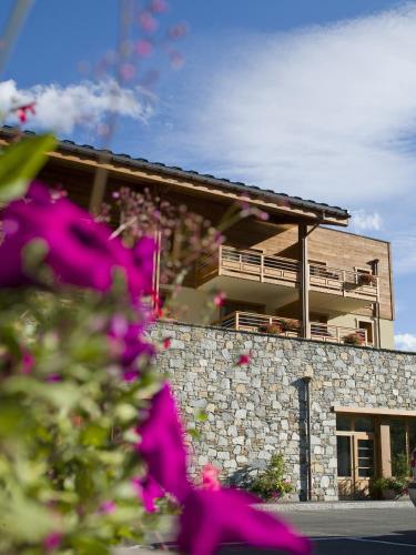 un bâtiment avec des fleurs roses devant lui dans l'établissement CGH Résidences & Spas Le Coeur d'Or, à Bourg-Saint-Maurice