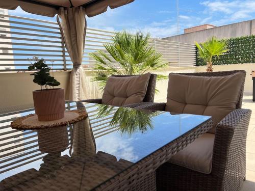 una mesa de cristal y sillas en un patio en Piso con terraza a 5 min del mar, en Alcanar