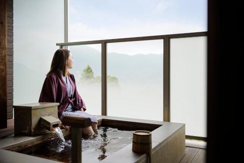 a woman sitting in a bath tub looking out of a window at Laforet Hakone Gora Yunosumika in Hakone