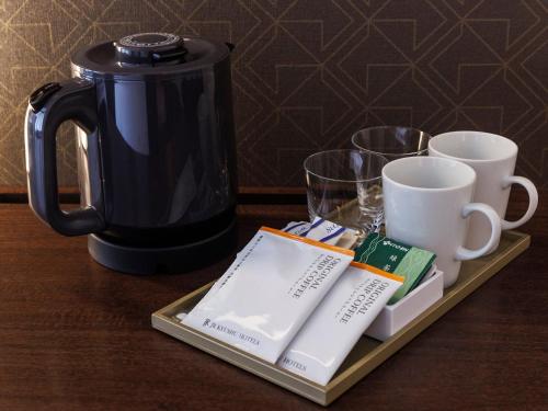 a tray with a coffee pot and cups on a table at JR Kyushu Hotel Blossom Fukuoka in Fukuoka