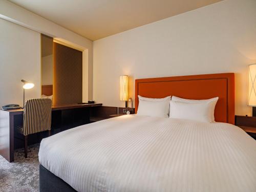 a hotel room with a large bed and a desk at JR Kyushu Hotel Blossom Fukuoka in Fukuoka