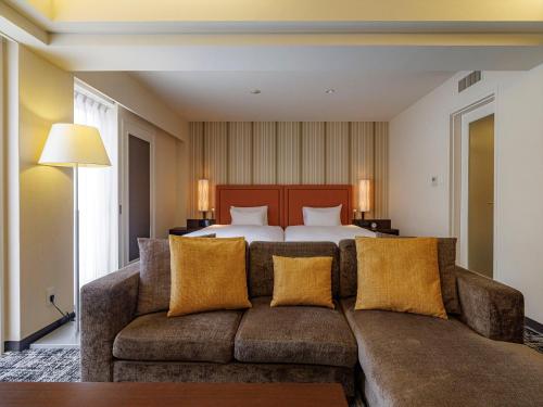 a living room with a couch and a bed at JR Kyushu Hotel Blossom Fukuoka in Fukuoka