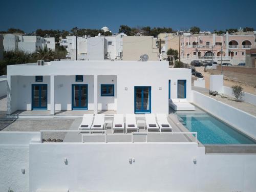 a white house with chairs and a swimming pool at Thadeos Villa with private jetted Pool in Fira