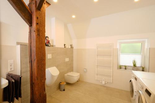 a white bathroom with a toilet and a window at Ferienwohnung Schwarting in Wiefelstede