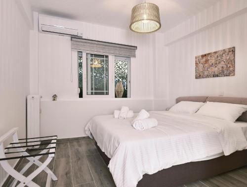 a white bedroom with a large bed and a window at "Under the olive tree"- Beautiful apartment in the heart of Athens in Athens