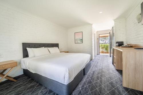 ein Schlafzimmer mit einem großen weißen Bett und einem Fenster in der Unterkunft Lakeview Hotel Motel in Shellharbour