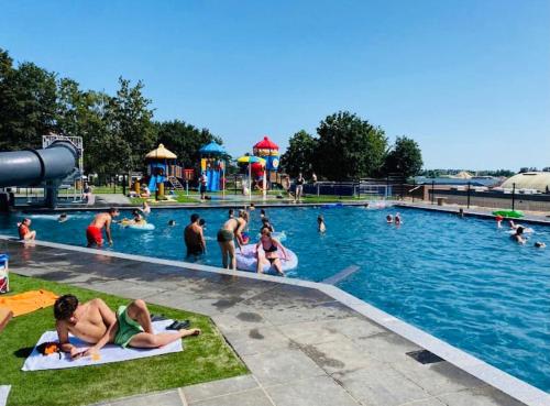 eine Gruppe von Personen in einem Pool in einem Wasserpark in der Unterkunft Ferienhaus LuxChalet VAJU IJsselView direkt am Fluss See Pool Park in Lathum