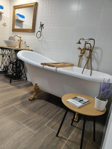 a bathroom with a tub and a sink and a table at Casuta din Cotroape - Maramureș in Săcel